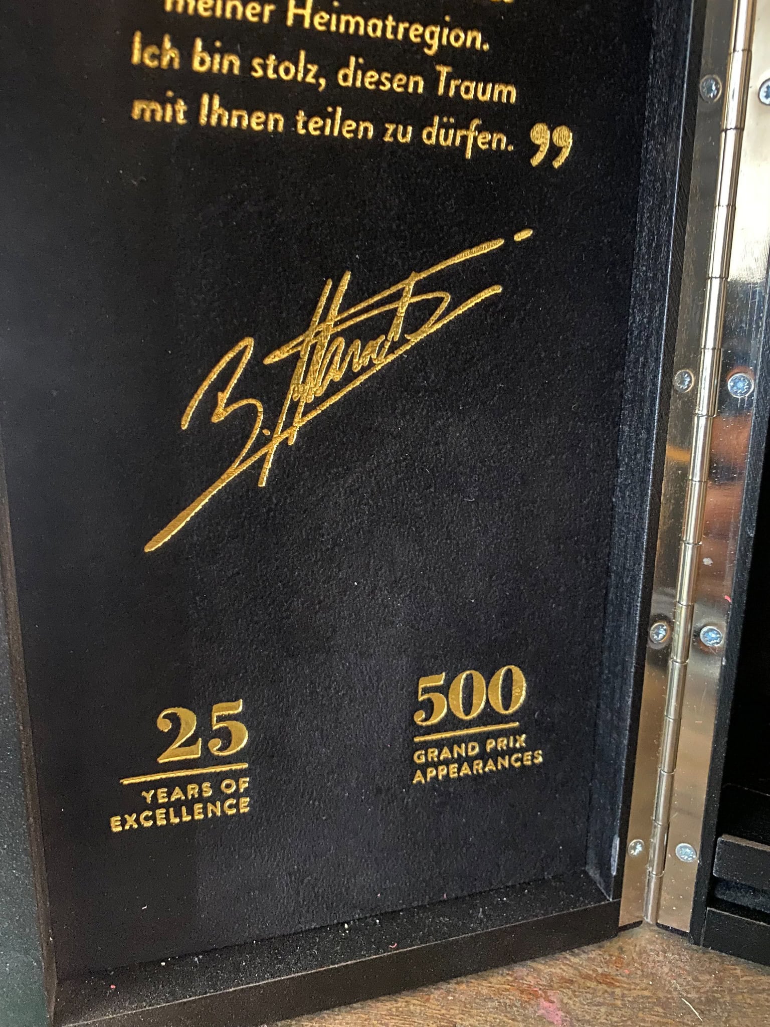 Signature and text on a black background with gold lettering.