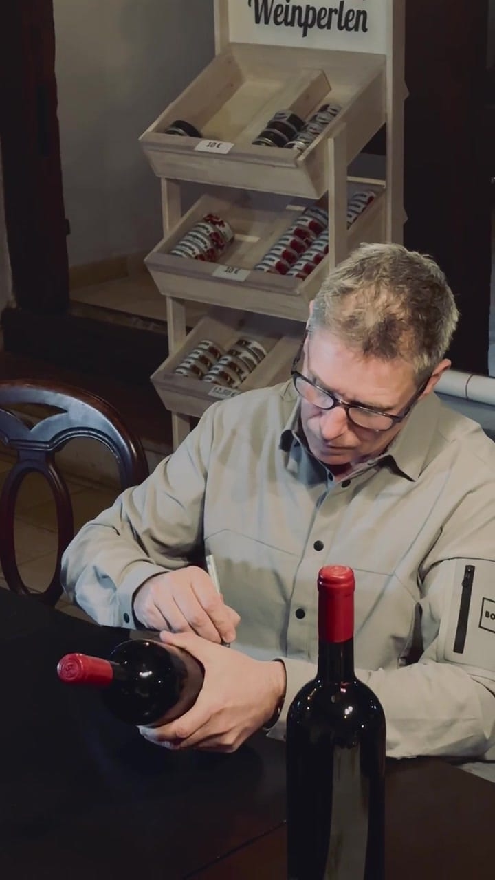 Man examining a bottle of Mayländer wine at a tasting event.